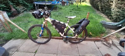Photo client : vélo équipé pour le bikepacking dans un jardin, porte-bagages à l'arrière