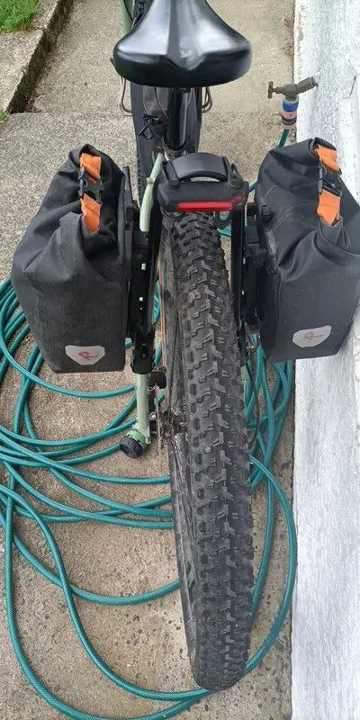 Photo client : VTT vert vu de dos avec une sacoche de chaque côté de la roue arrière