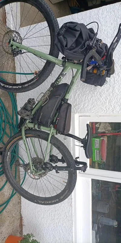 Photo client : VTT vert vu de côté avec le porte-bagages arrière et ses sacoches