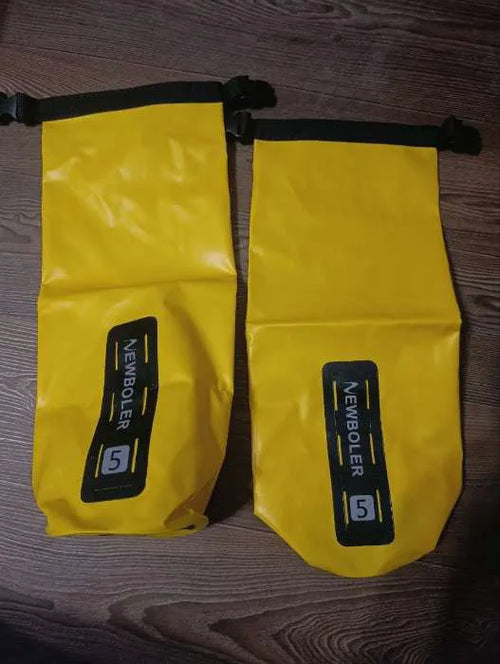 Deux sacoches de fourche vélo étanches 5 L jaunes à fermeture enroulable, posées sur un parquet