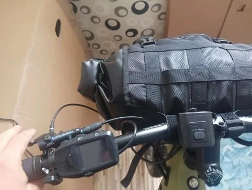 Sacoche de guidon étanche sanglée dans son harnais sur le cintre d'un VTT électrique, vue du poste de pilotage
