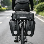 Cycliste vu de dos sur route, sacoche de dessus et 2 sacoches latérales fixées au porte-bagages arrière