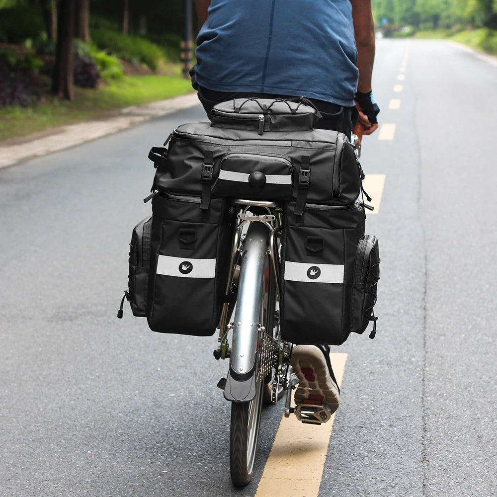 Cycliste de dos sur une route avec sacoches de porte-bagage noires 3 en 1 installees sur son velo.