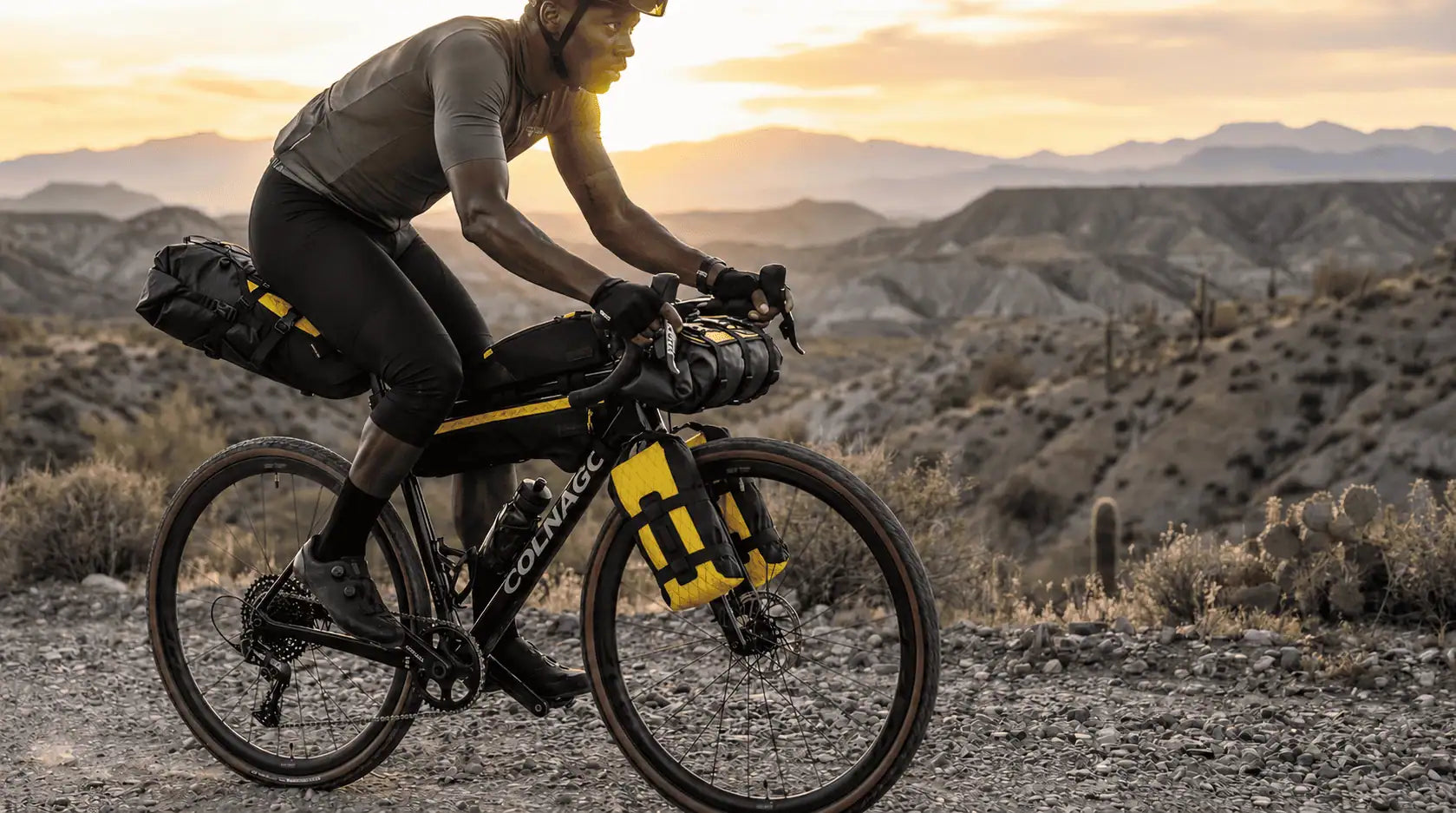 Cycliste sur velo de route equipe de sacoches de cadre jaunes et noires dans un paysage desertique.