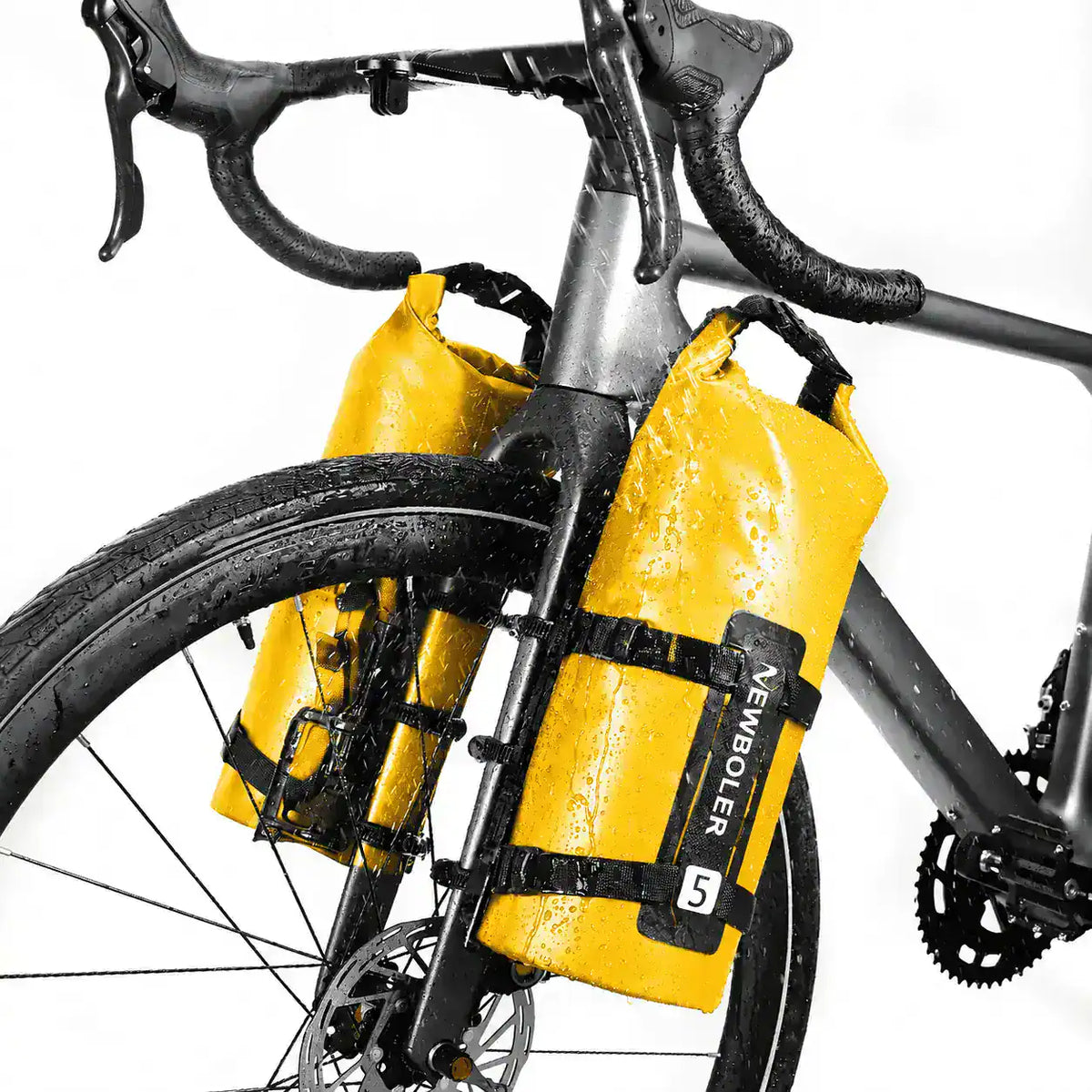 Deux sacoches cylindriques jaunes fixees sur les fourches d un velo de route sous la pluie vue en contre plongee.