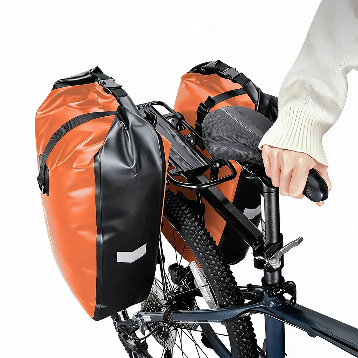 Deux sacoches orange et noires fixees de chaque cote du porte-bagage arriere d un velo tout-terrain.