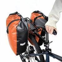 Deux sacoches orange et noires fixées sur le porte-bagages arrière d'un vélo tout-terrain