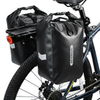 Deux sacoches imperméables noires installees sur le porte-bagage arriere d un velo, vues de profil.