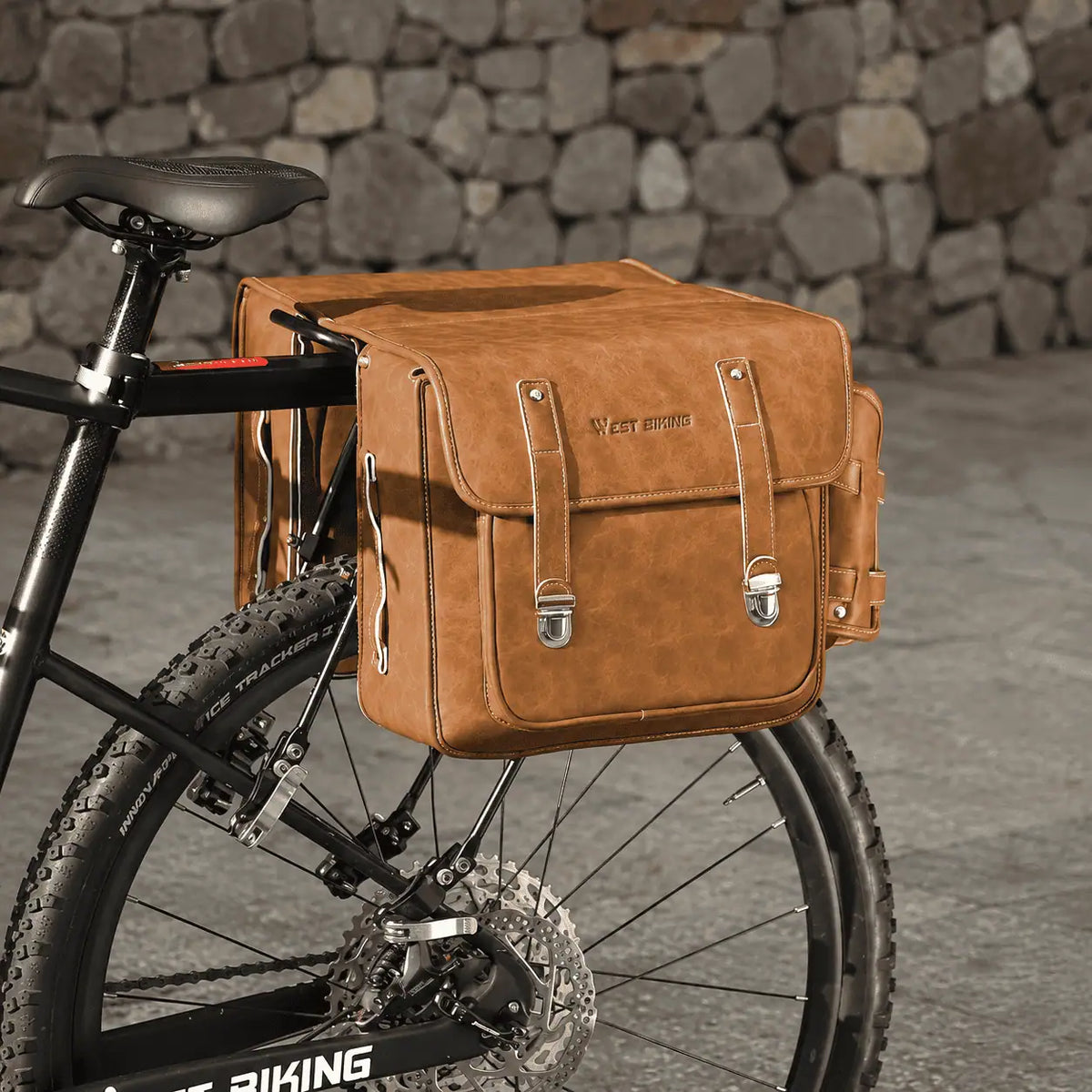 Double sacoche caramel en cuir fixee sur le porte-bagage arriere d'un VTT.