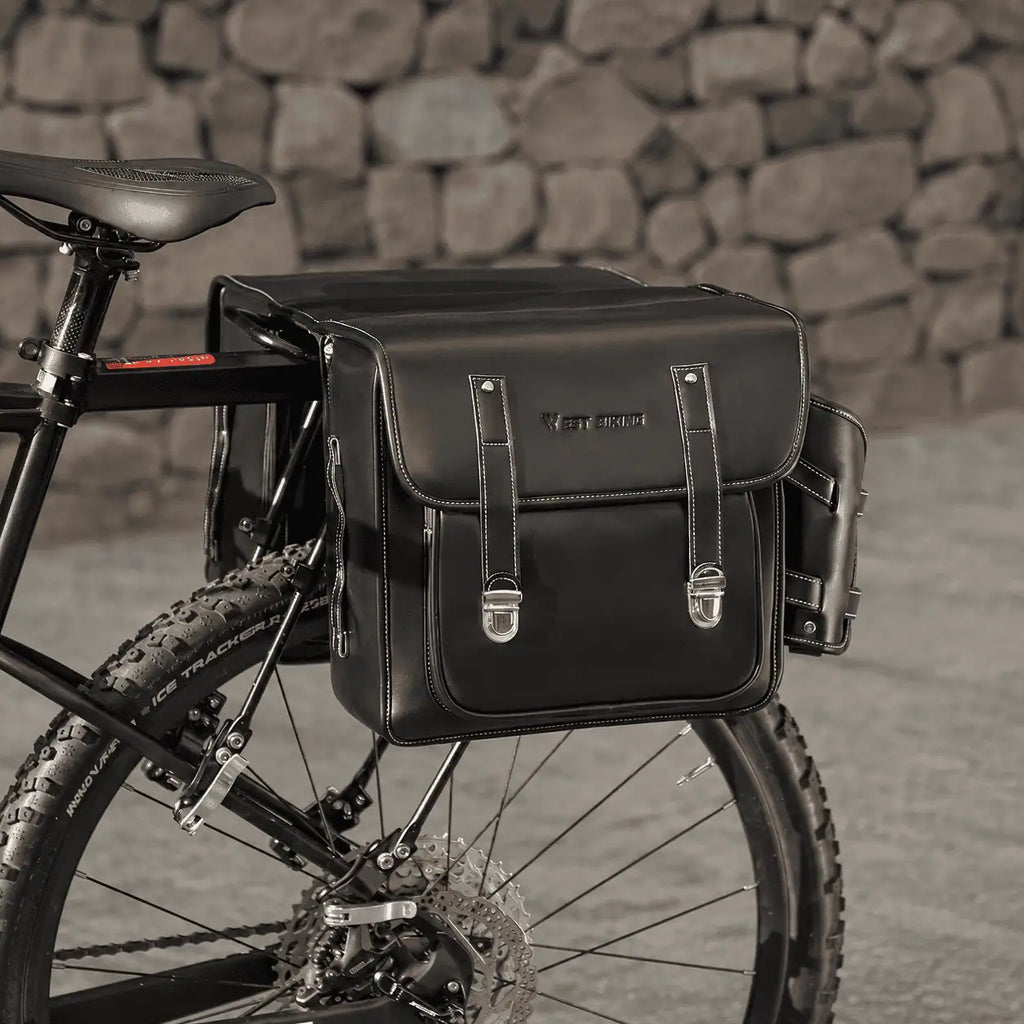 Double sacoche noire en cuir fixee sur le porte-bagage arriere d'un VTT.