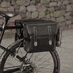 Double sacoche noire en cuir fixee sur le porte-bagage arriere d'un VTT.