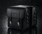 Double sacoche noire sous la pluie sur fond sombre, illustration de son etancheite.