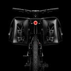 Vue arriere d'un velo equipe de deux grandes sacoches noires avec porte-bidons et feu rouge.