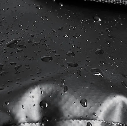 Gros plan sur des gouttelettes d eau glissant sur le tissu impermeable d une sacoche velo en noir et blanc.
