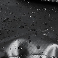 Gros plan sur des gouttelettes d eau glissant sur le tissu impermeable d une sacoche velo en noir et blanc.