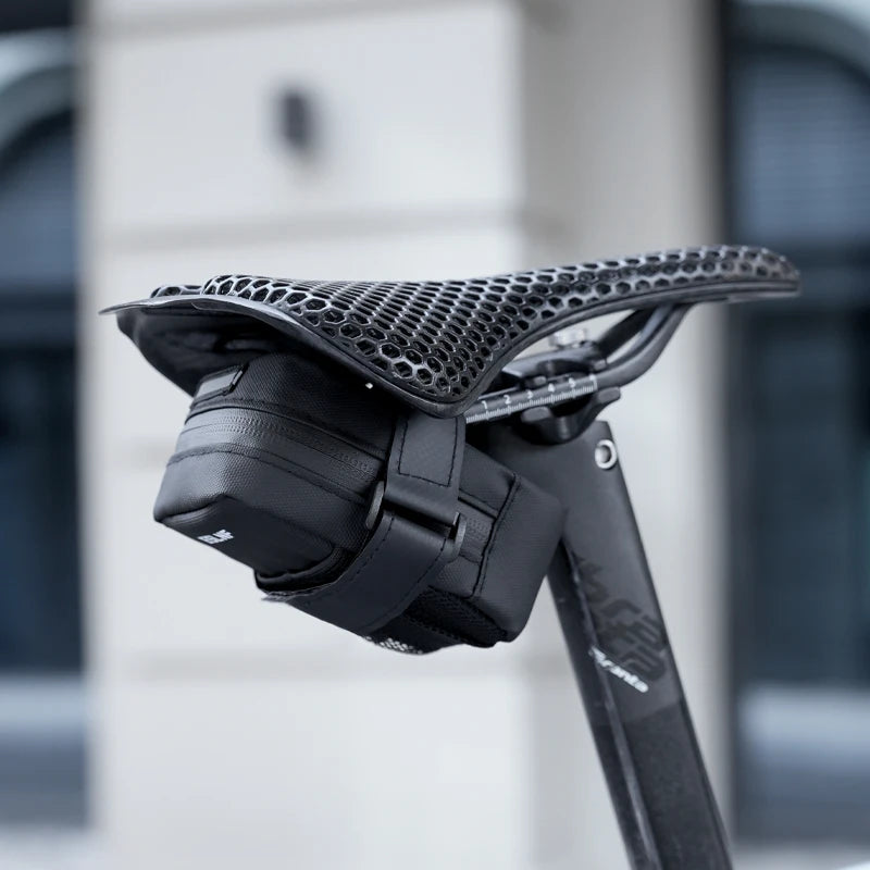Petite sacoche de selle vélo noire ESLNF fixée sous une selle ajourée, vue de côté