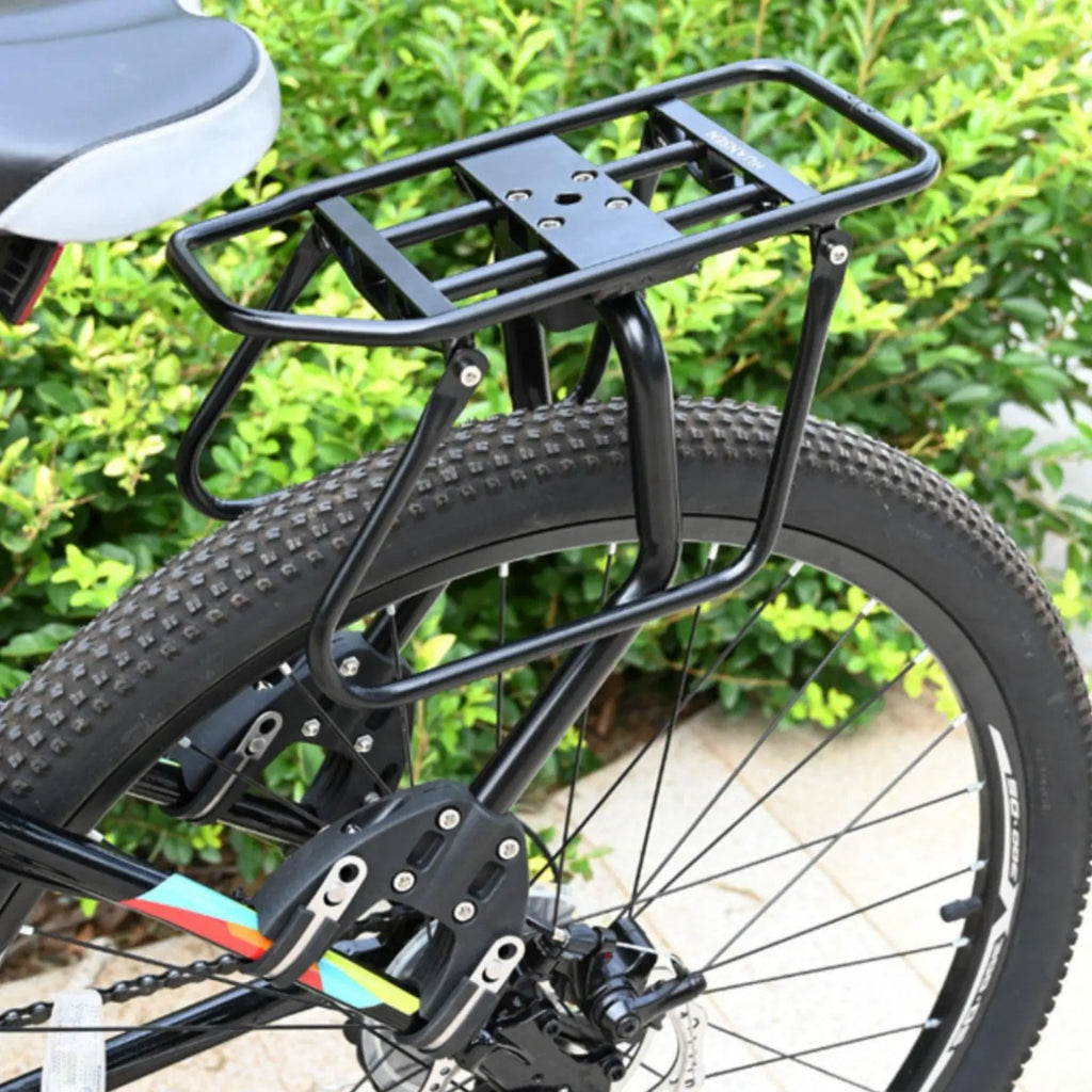 Porte-bagage arrière à plateau tubulaire et arceaux latéraux monté sur un VTT, pinces serrées près de l'axe