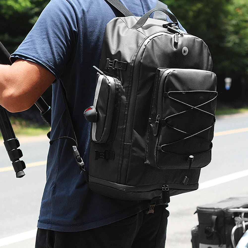 Cycliste portant un sac a dos noir avec poches multiples et lacets elastiques, sur une route en exterieur.