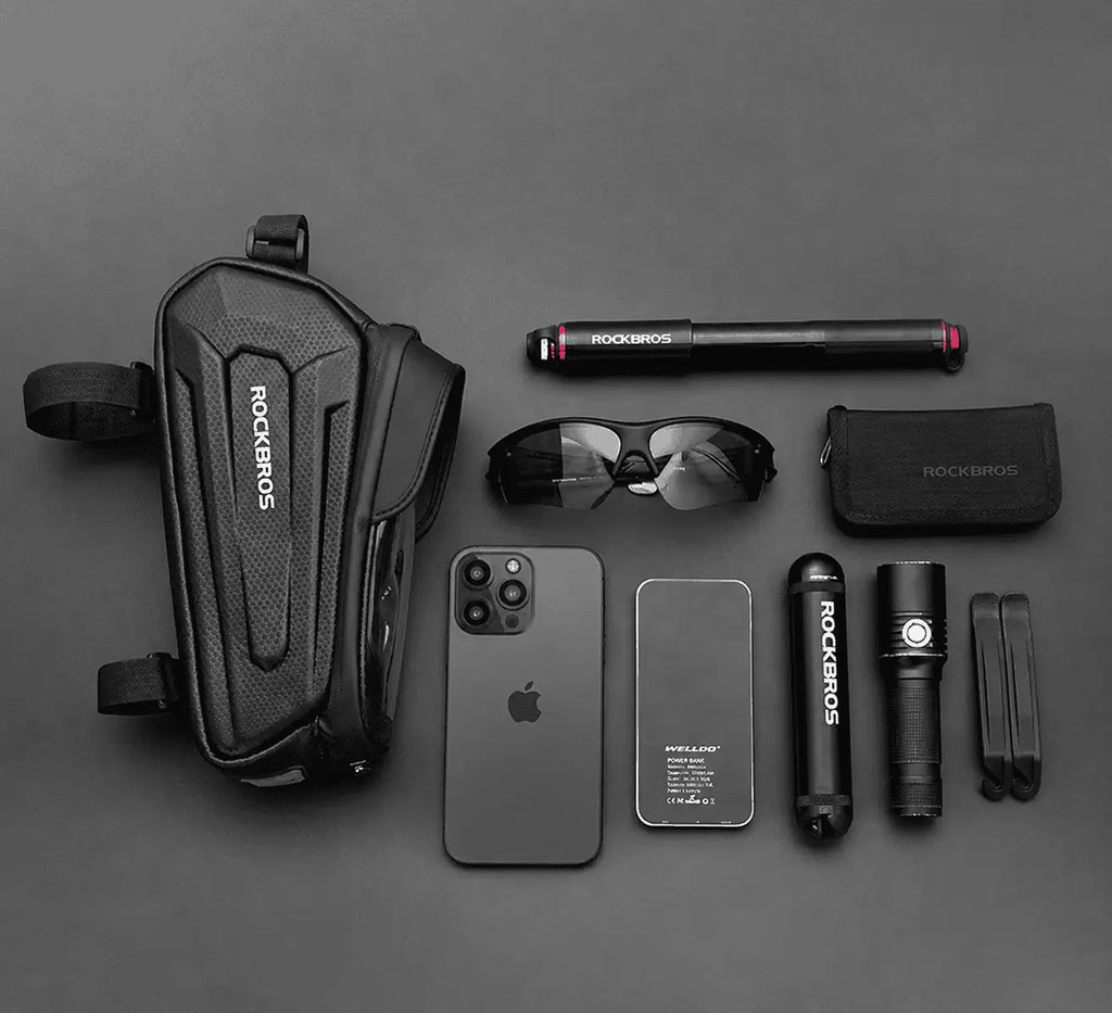 Sacoche de cadre vélo posée avec un téléphone, des écouteurs, une batterie et des outils