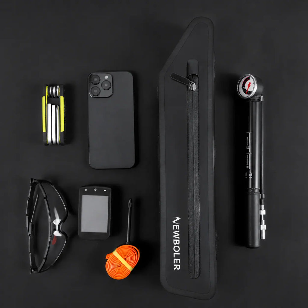 Sacoche de cadre velo noire posee avec des accessoires de cyclisme : pompe, multi-outil, telephone, lunettes et GPS.