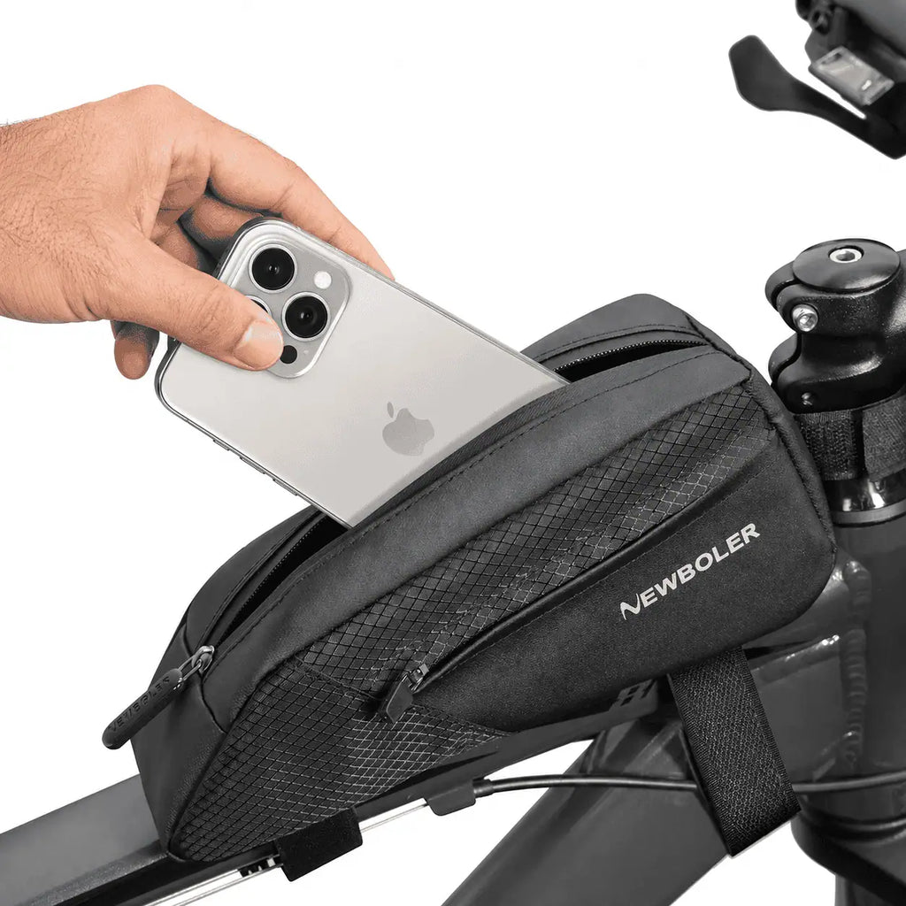 Main inserant un smartphone dans la poche superieure d'une sacoche de cadre velo noire