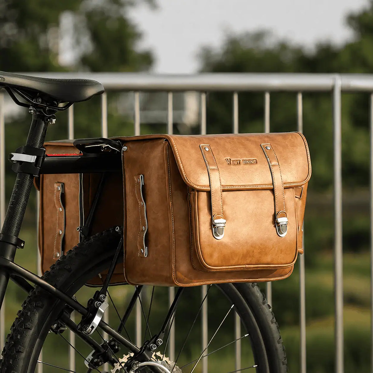 Sacoche en cuir cognac fixee sur le porte-bagage arriere d'un VTT, vue de cote.