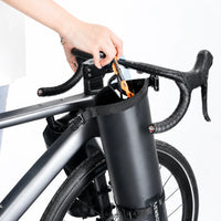 Main fixant une sacoche de fourche noire sur la fourche d'un vélo de route