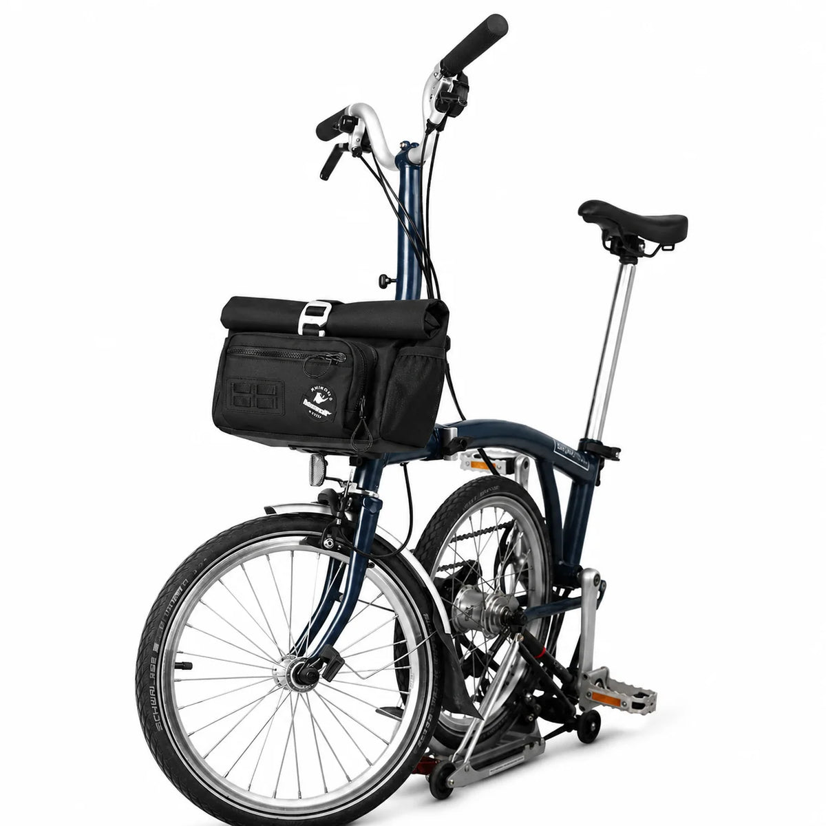 Sacoche de guidon noire fixée à l'avant d'un vélo pliant bleu marine, vue de côté sur fond blanc.