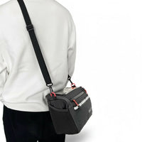 Sacoche de guidon vélo noire portée en bandoulière sur un sweatshirt blanc