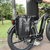 Sacoche laterale noire impermeable fixee sur le porte-bagage arriere d'un velo electrique fat bike, en exterieur.