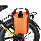 Sacoche laterale orange avec fermeture a rouleau fixee sur le porte-bagage arriere d'un fat bike.