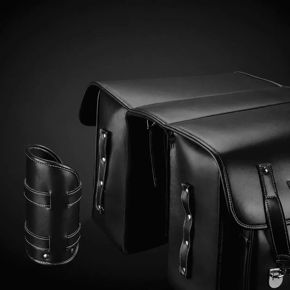 Sacoche noire en cuir presentee avec son porte-bidon cylindrique sur fond sombre.