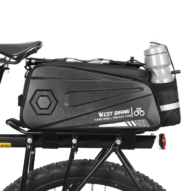 Sacoche de porte bagage arriere noire avec porte bidon integre montee sur un velo a gros pneus.
