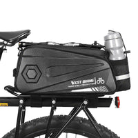 Sacoche de porte bagage arriere noire avec porte bidon integre montee sur un velo a gros pneus.
