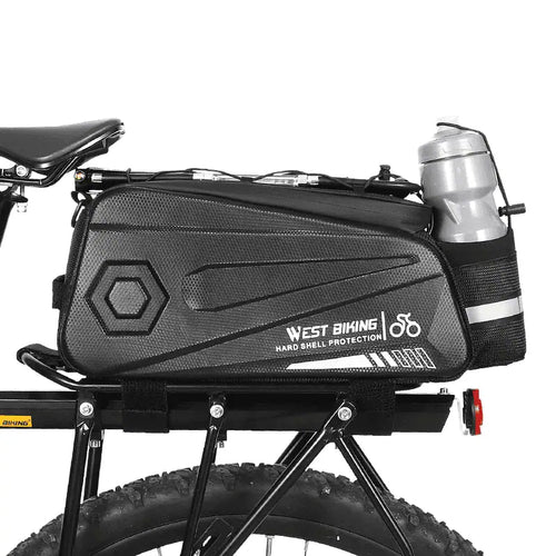 Sacoche de porte bagage arriere noire avec porte bidon integre montee sur un velo a gros pneus.