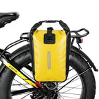 Sacoche jaune etanche fixee sur le porte-bagage arriere d un velo a gros pneus, vue de cote.