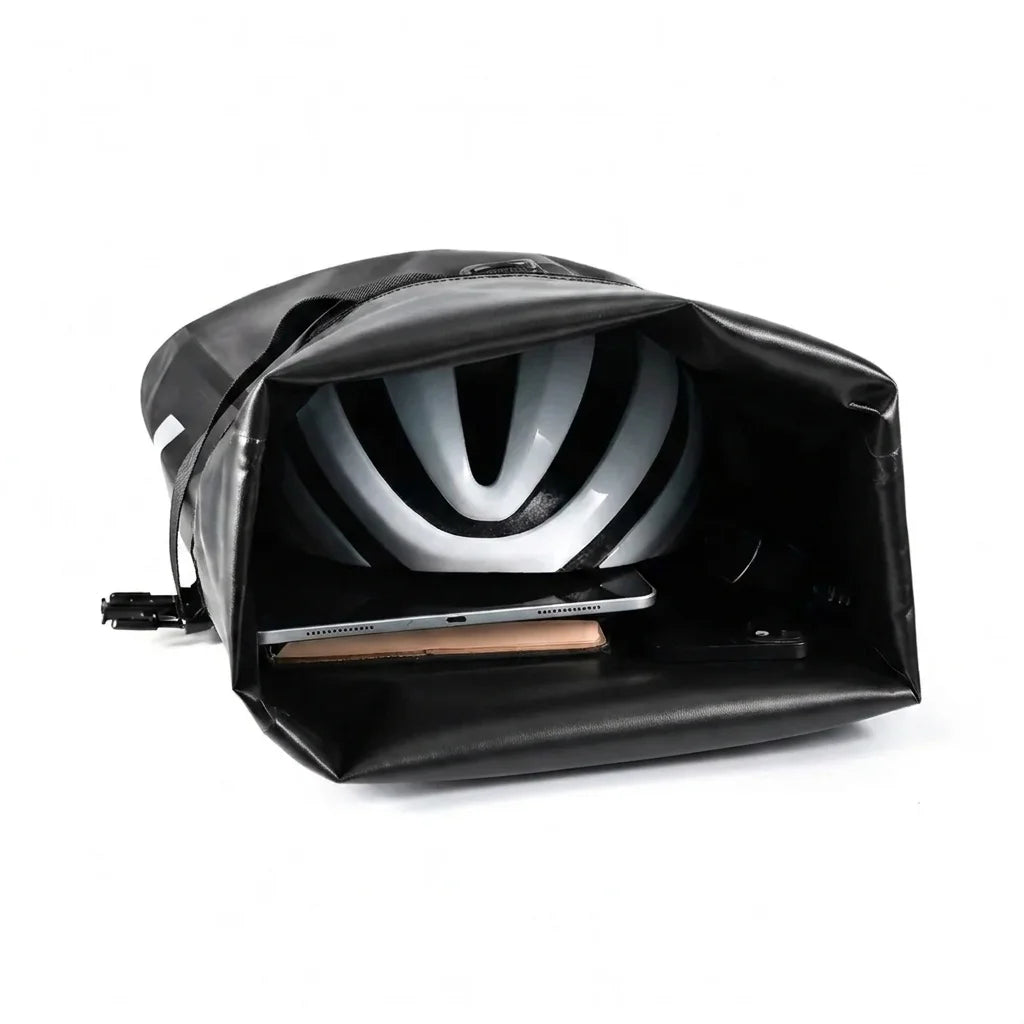 Sacoche de porte-bagage noire ouverte avec un casque de velo et un ordinateur portable a l interieur, fond blanc.