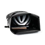 Sacoche de porte-bagage noire ouverte avec un casque de velo et un ordinateur portable a l interieur, fond blanc.