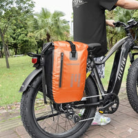 Grande sacoche de porte-bagage orange fixée sur un vélo électrique fat bike noir