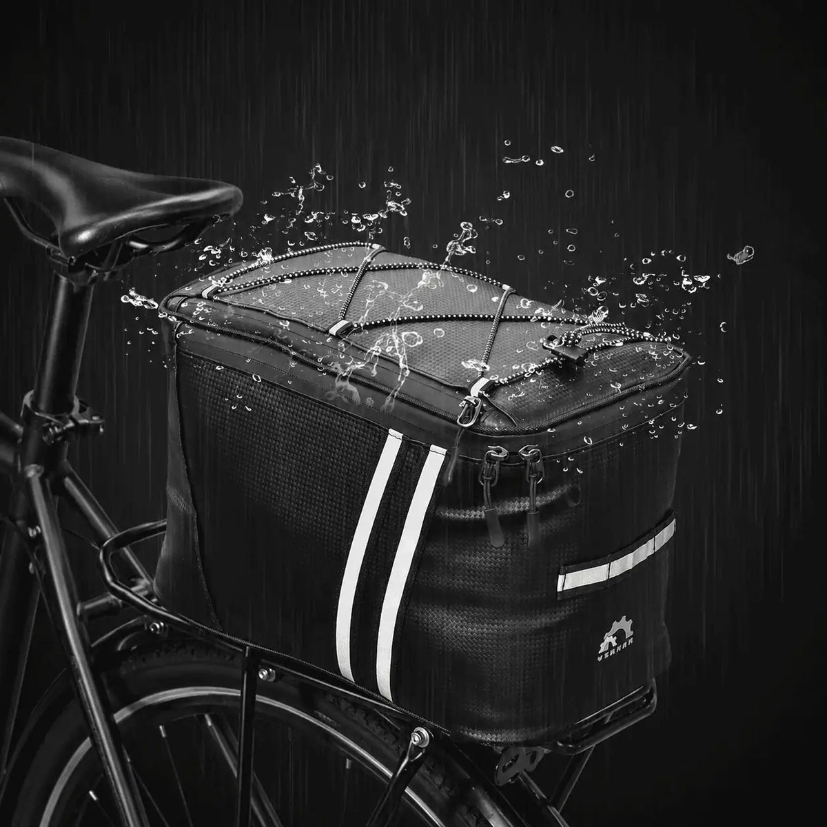 Sacoche de porte-bagage vélo noire installée sur un vélo sous la pluie, avec des éclaboussures d'eau illustrant son imperméabilité.
