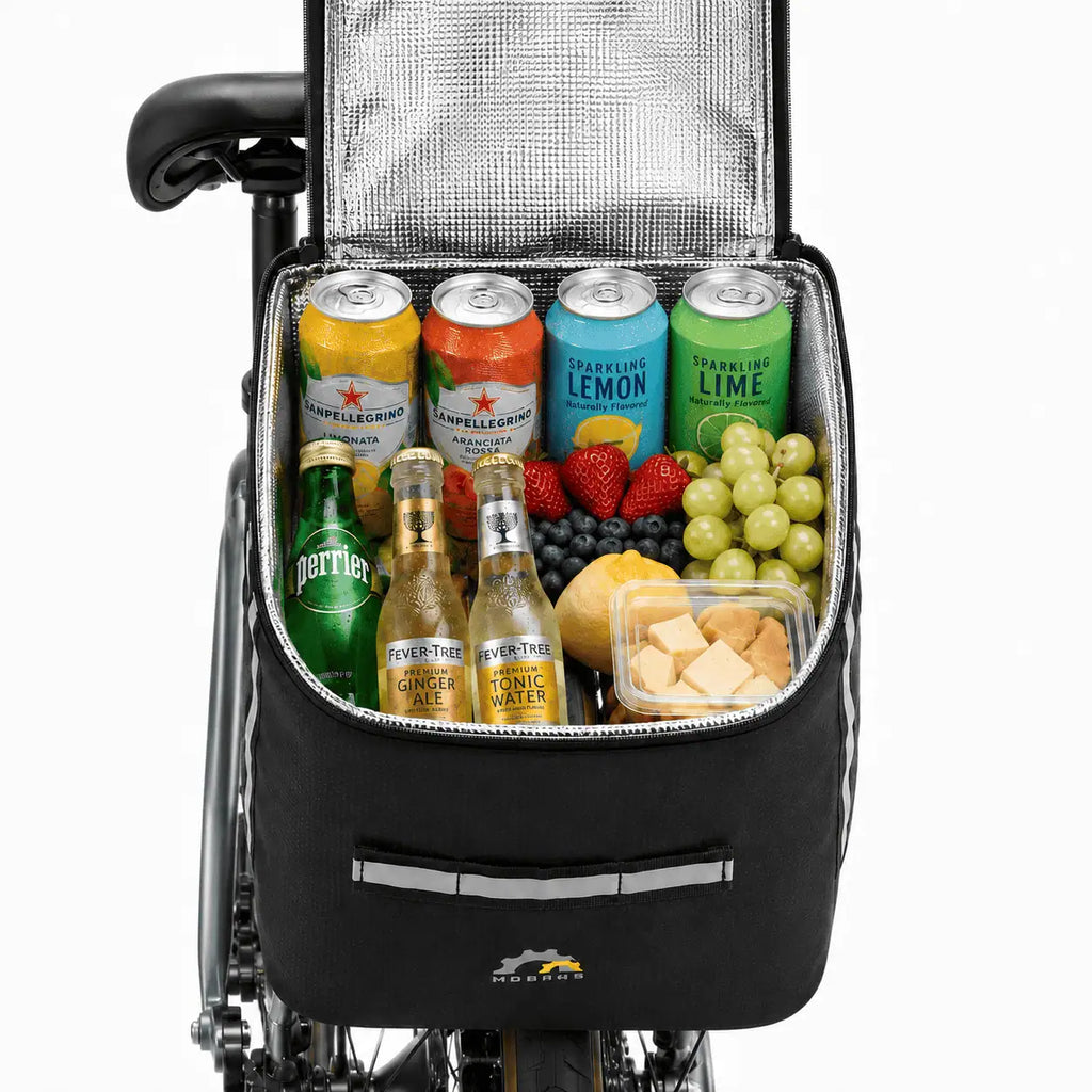Sacoche de porte-bagage vélo isotherme ouverte installée sur un vélo, compartiment rempli de boissons et de fruits.
