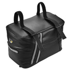 Sacoche de porte-bagage vélo noire vue de trois quarts, avec deux poignées de transport sur le dessus et bande réfléchissante grise.