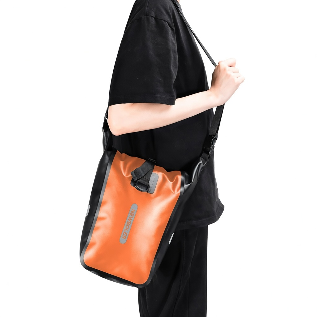 Sacoche de porte-bagages orange et noire portee en bandouliere par une personne habilee en noir.