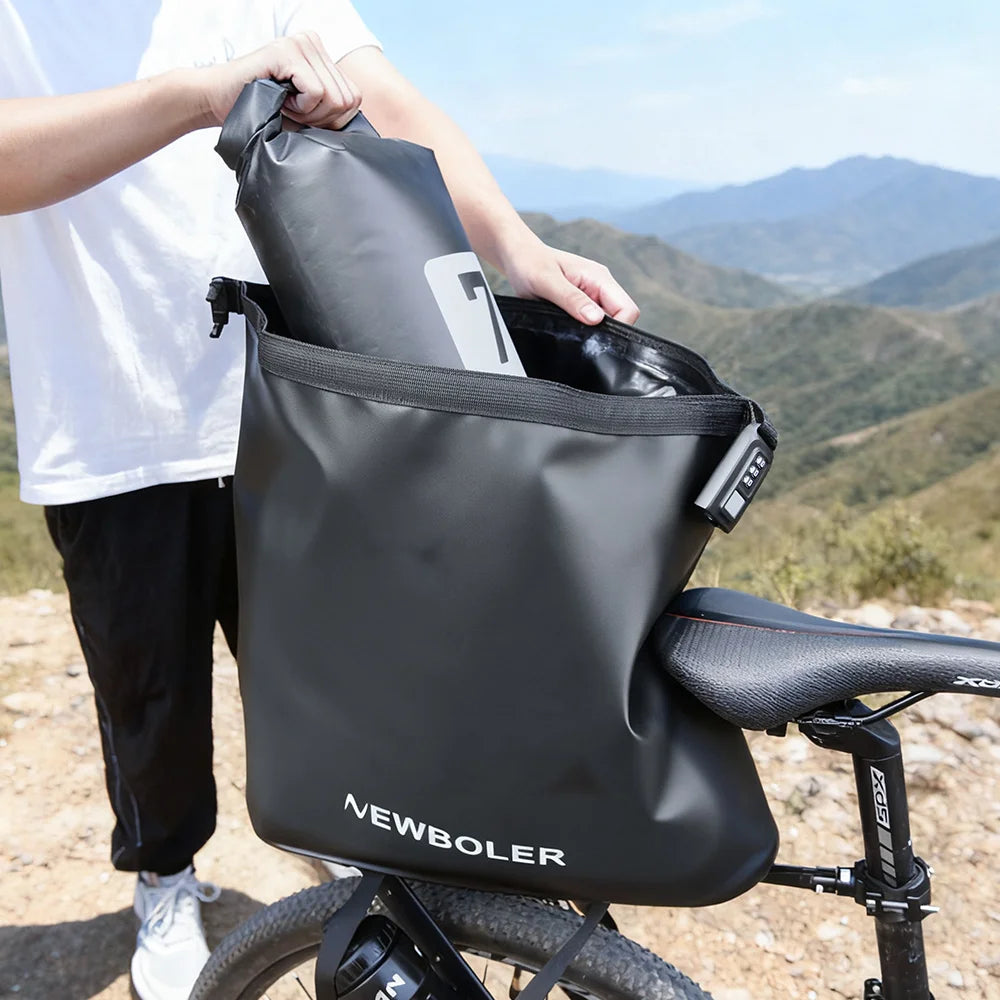 Personne ouvrant une grande sacoche de selle noire impermeable fixee sous la selle d'un velo, en pleine nature.