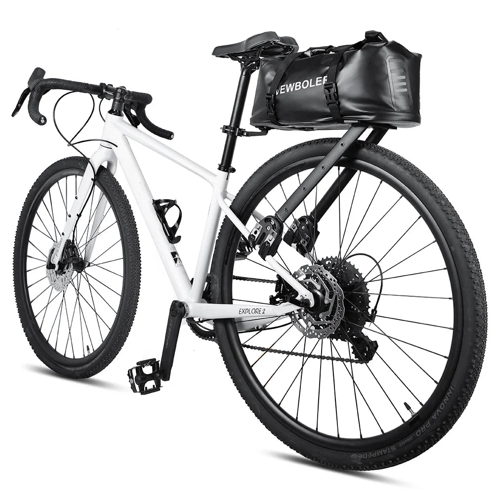 Sacoche de selle noire volumineuse fixee sous la selle d'un velo gravel blanc, presentee sur fond blanc.