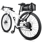 Sacoche de selle noire volumineuse fixee sous la selle d'un velo gravel blanc, presentee sur fond blanc.