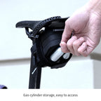 Main retirant une cartouche CO2 du filet de la sacoche de selle vélo montée sous la selle