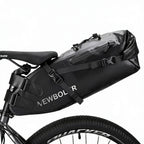 Grande sacoche de selle noire avec fermeture roll-top fixee sous la selle d'un velo VTT, vue de cote.