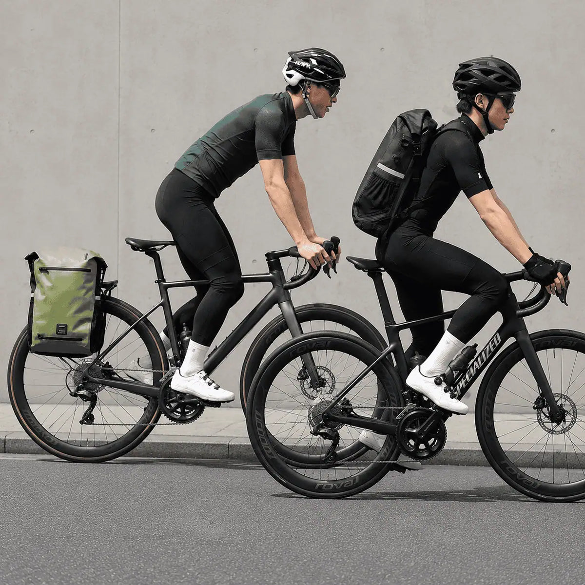Deux cyclistes sur route, le modèle vert fixé au porte-bagages et le modèle noir porté sur le dos