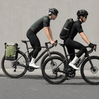 Deux cyclistes sur route, le modèle vert fixé au porte-bagages et le modèle noir porté sur le dos